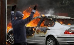 A silver BMW 3-Series car set alight during rioting in Ardoyne