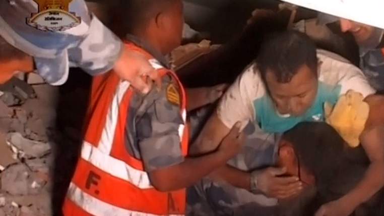 Rescue workers trying to pull people to safety after a massive earthquake in Nepal
