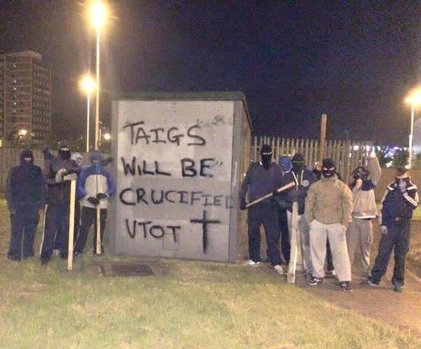 Masked loyalists beside a sinister message at Broadway roundabout in west Belfast