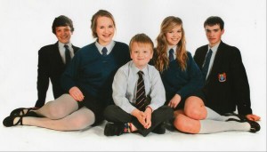 Aaron Macaulay sitting happily with his four older brothers and sisters for a sibling picture