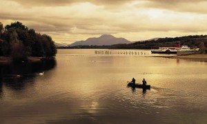 Two people canoeing in Scotland's Loch Lomond as the sun sets