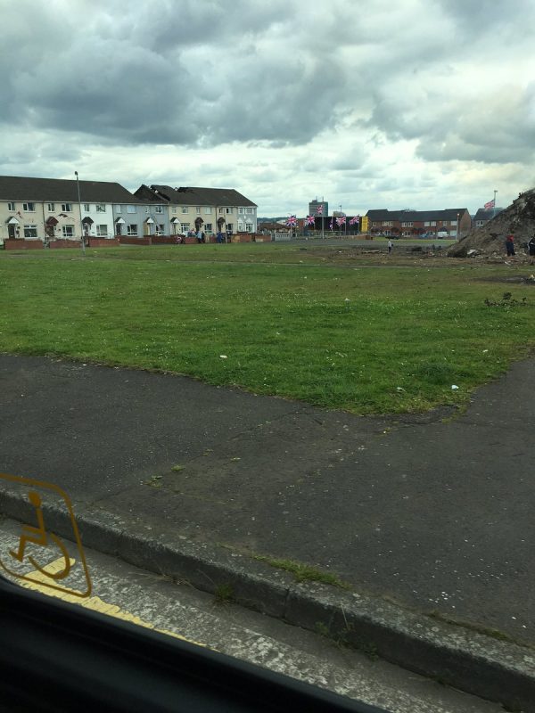 The aftermath of the Shankill bonfire still smoulders while two houses in the background have been left gutted after red hot embers set roofs ablaze