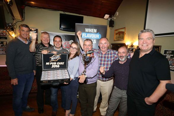 MEETING OF MIGHTY MINDS!
The Mighty Wanderers, a pub quiz team made up of six members from Omagh has been named the smartest in the country after winning the seventh annual McCoys NI Pub Quiz and bagging a tasty cash prize of £1,000. The Mighty Wanderers from Omagh battled it out against the best brains from all over Northern Ireland to lift the coveted title for the first time at the Errigle Inn in Belfast. The calibre of the teams on display was highly impressive with quiz veterans from TV shows The Chase, Tipping Point, Weakest Link, Mastermind and Eggheads all doing their best to outwit each other on the night. This years quiz was part of the McCoys When Flavour Calls campaign and there was plenty of flavour during the finale with music, picture, TV and general knowledge rounds all served up by quizmaster and U105 presenter Johnny Hero to get peoples brains ticking. Pictured with Ricky Watts from McCoys (far left) and U105s Johnny Hero (far right) are The Mighty Wanderers (l-r) Gerry Raflewski, Susan McCaughey, Mark Duffy, Michael Duffy, John Rafferty and Tony McConnell.