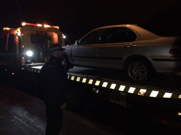 TSG officer watches on as a car which skidded into police checkpoint is seized and taken to car pound